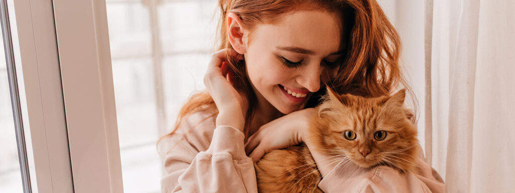 Photo d'une femme rousse avec son chat roux heureux pour le nouveau logo de l'association restos du chat designé par Madame Bold